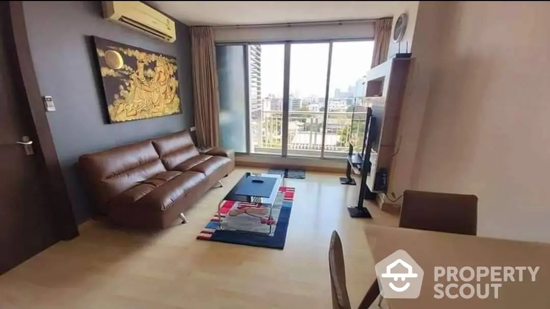 Spacious living room with large windows, leather sofa, and modern decor, offering a comfortable urban living experience.