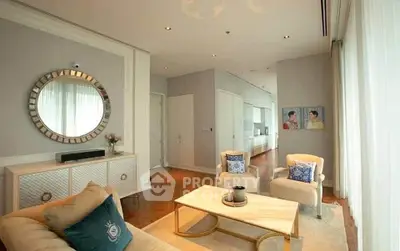 Luxurious living room with elegant decor and natural light, featuring plush seating and stylish mirror.