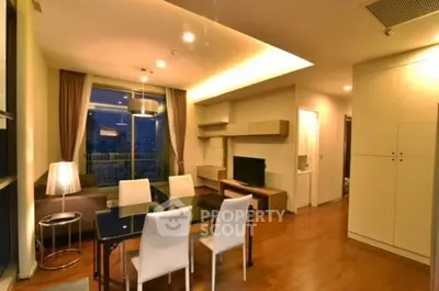 Modern living room with elegant dining area and city view balcony at night.