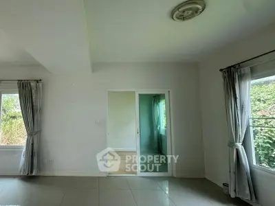 Spacious room with large windows and sliding glass door, offering abundant natural light and garden views.