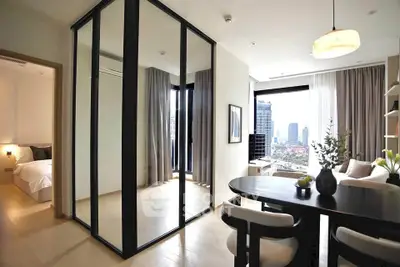Modern apartment interior with dining area and city view, featuring sleek design and natural light.
