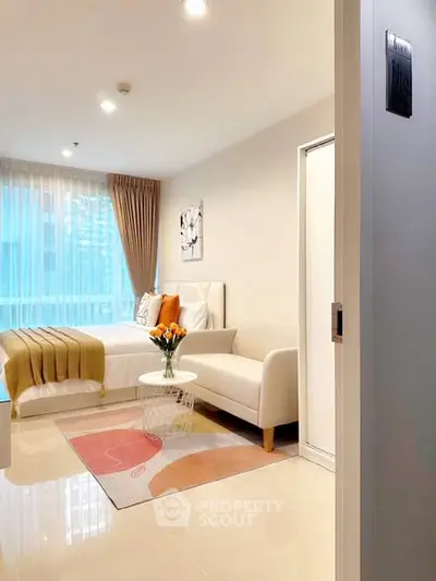 Modern bedroom with cozy seating area and large window, perfect for relaxation.