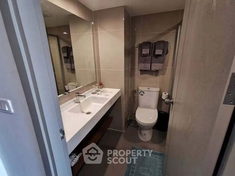Modern bathroom with sleek fixtures and large mirror in a contemporary apartment.