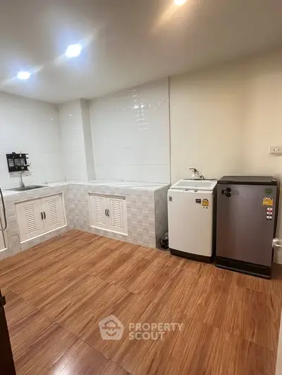 Spacious laundry room with modern appliances and wooden flooring