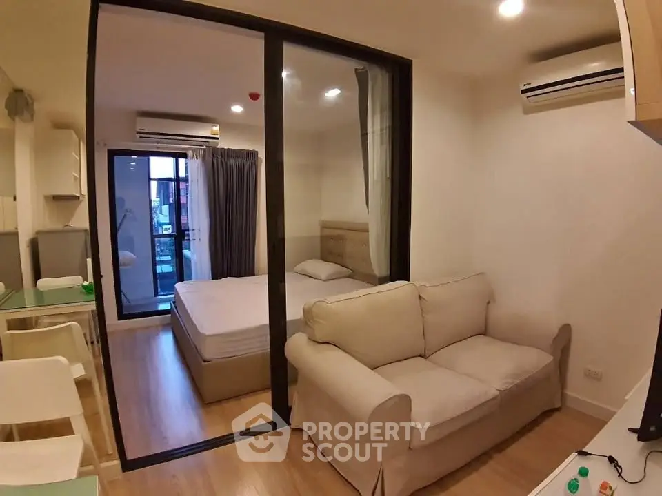 Modern studio apartment with cozy living area and bedroom separated by glass sliding doors.