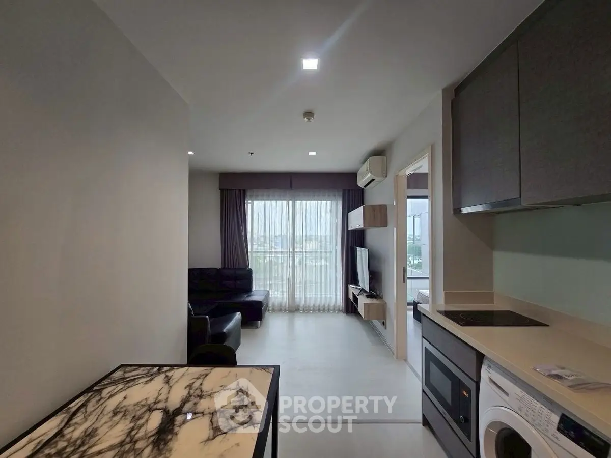 Modern apartment interior with open kitchen and living room, featuring sleek appliances and stylish decor.