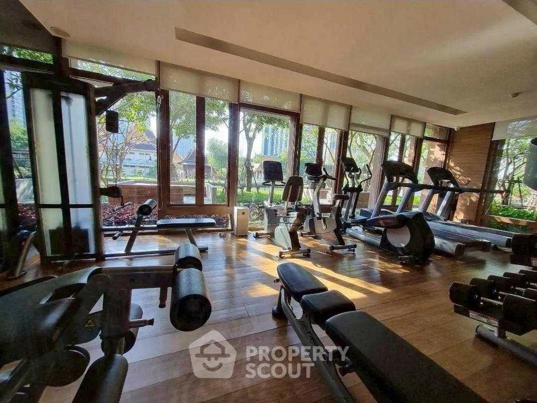 Spacious gym with modern equipment and large windows offering garden views.