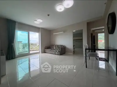 Spacious living room with large windows and modern decor in a high-rise apartment.