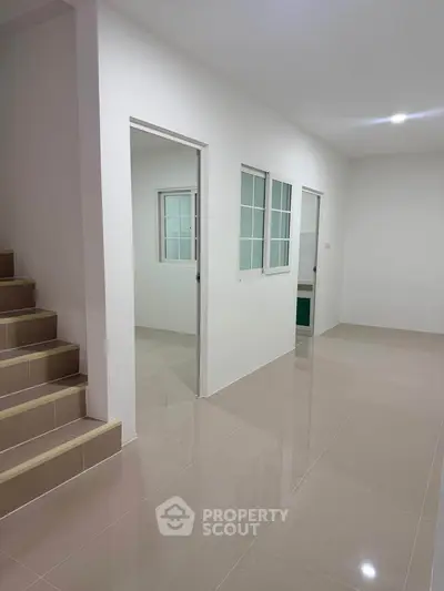 Spacious modern hallway with sleek tile flooring and staircase in a contemporary home.