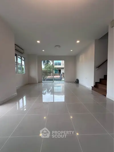 Spacious modern living room with large windows and glossy tiled floors