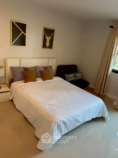 Cozy bedroom with stylish decor and natural light, perfect for relaxation.