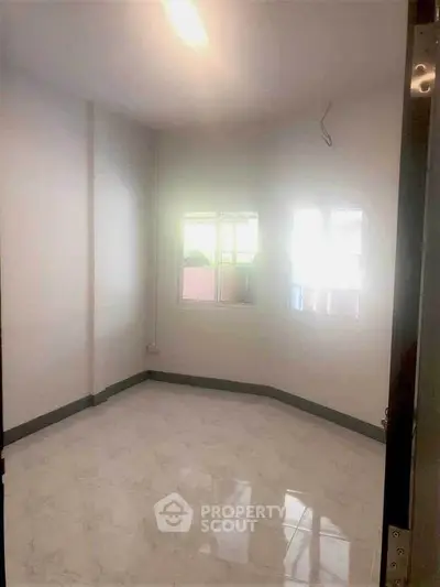 Spacious empty room with glossy marble flooring and bright natural light.