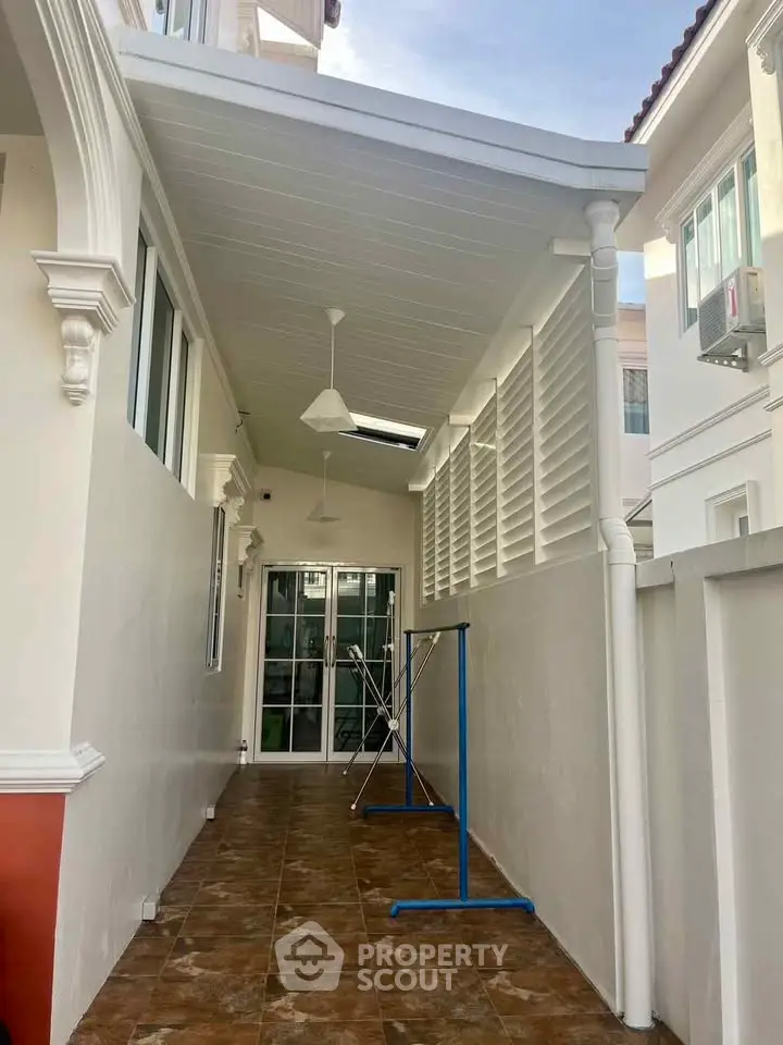 Charming covered outdoor corridor with tiled flooring and ceiling fans in modern home