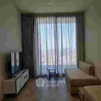 Modern living room with large window and city view, featuring a sleek TV stand and comfortable seating.