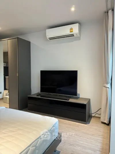 Modern bedroom with sleek TV setup and air conditioning unit.