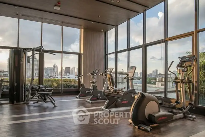 Luxurious gym with city view and modern fitness equipment in high-rise building.