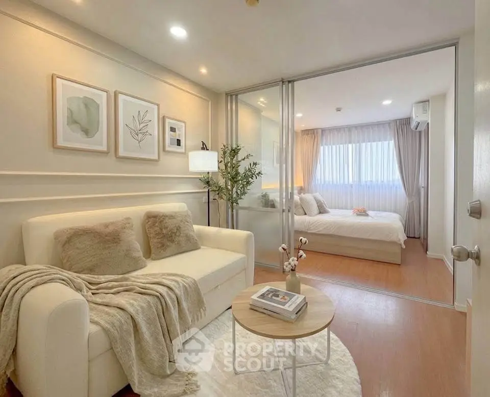 Modern apartment interior with cozy living room and elegant bedroom separated by glass doors.