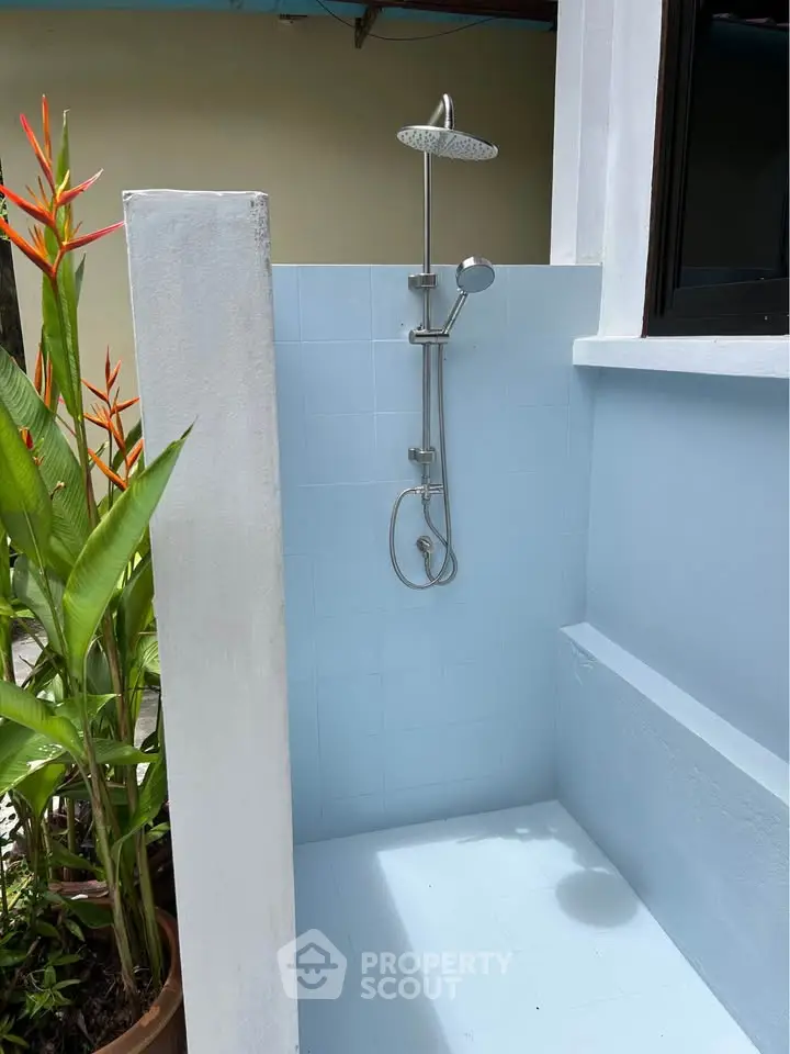 Charming outdoor shower area with modern fixtures and lush greenery, perfect for a refreshing experience.