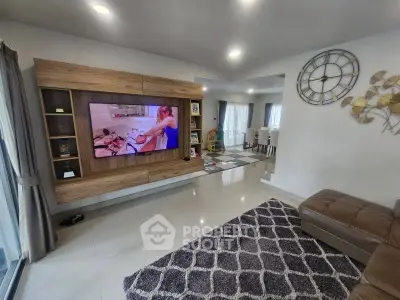 Spacious modern living room with large TV, stylish decor, and open dining area.