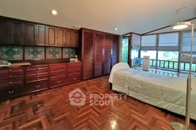 Spacious bedroom with wooden flooring and large windows offering natural light.