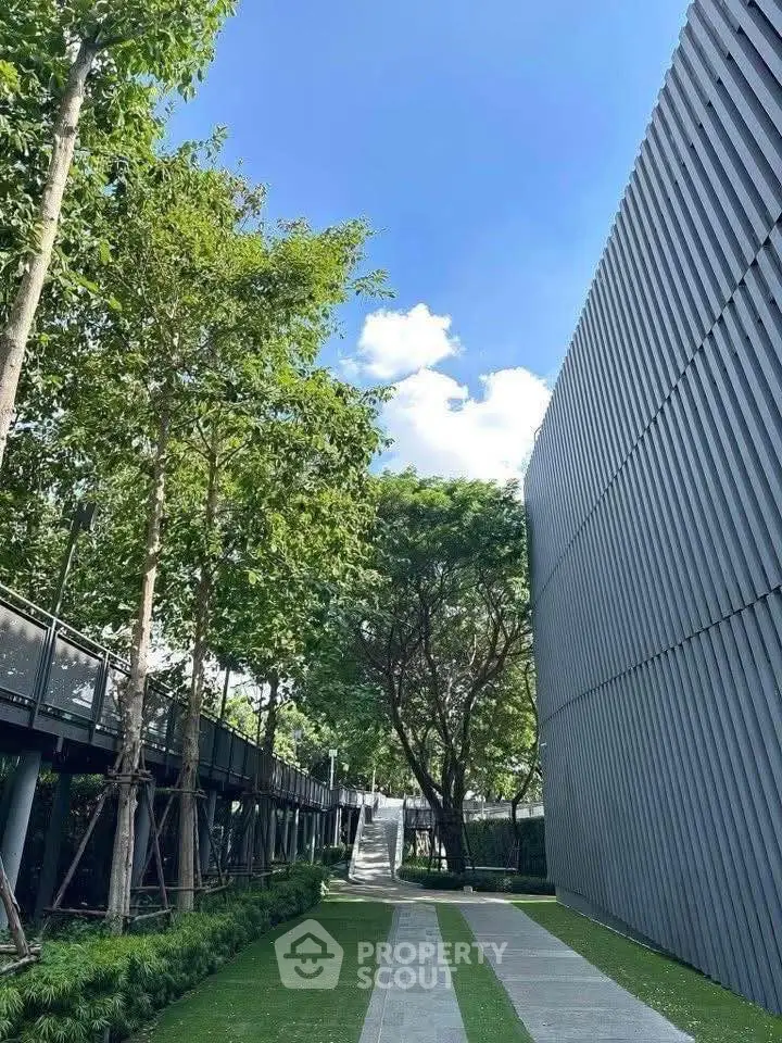 Modern building exterior with lush greenery and clear blue sky
