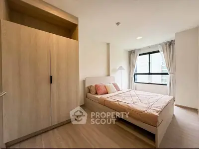 Modern bedroom with large window and wooden wardrobe in a stylish apartment.