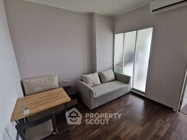 Cozy living room with modern sofa, wooden floor, and air conditioning.