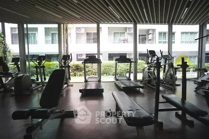 Modern gym with exercise equipment and large windows in residential building