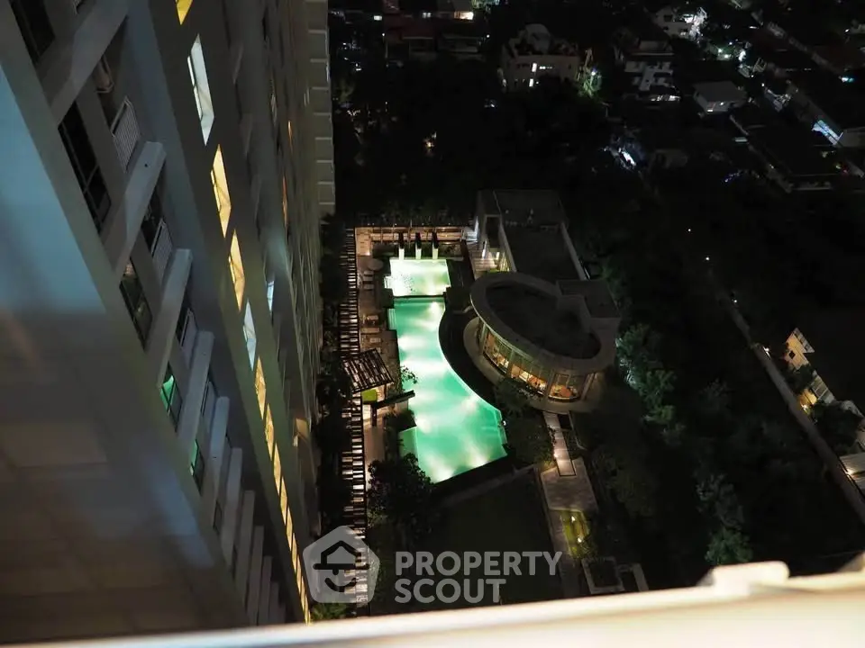Stunning aerial view of illuminated swimming pool in luxury apartment complex at night.