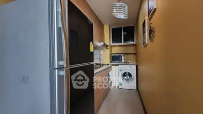 Modern kitchen with sleek appliances and washing machine in compact layout.