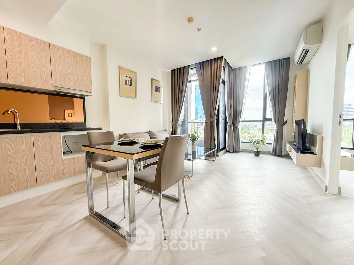 Modern open-plan living room with sleek kitchen and city view balcony.