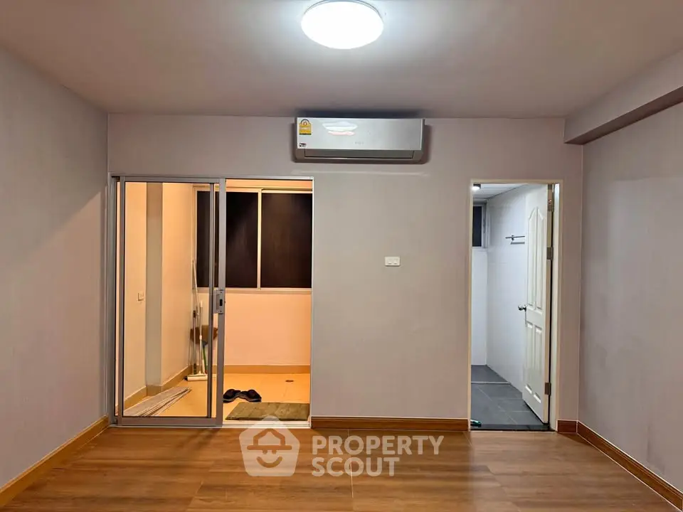 Spacious unfurnished room with wooden flooring and air conditioning, ideal for customization.