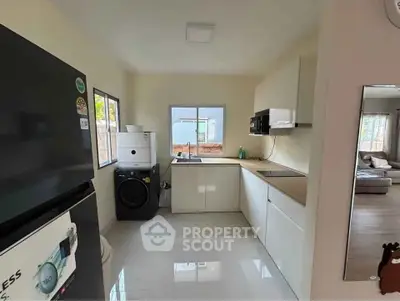 Modern kitchen with sleek appliances and open layout, featuring a washing machine and ample natural light.