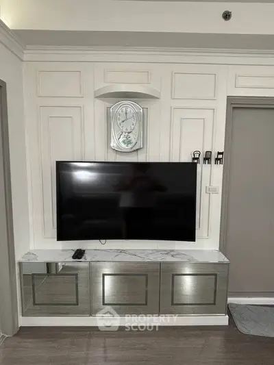 Stylish living room with wall-mounted TV and elegant clock, featuring modern decor and sleek cabinetry.