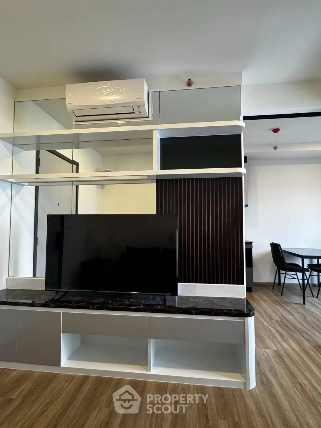 Modern living room with sleek TV unit and air conditioning, featuring stylish wood flooring and contemporary design.