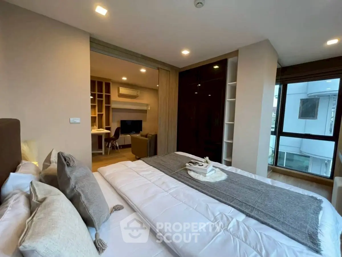 Modern bedroom with cozy decor and view into stylish living area