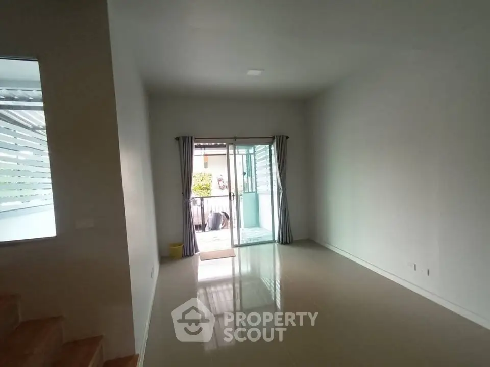 Spacious empty living room with glossy floor and sliding glass doors leading to balcony.
