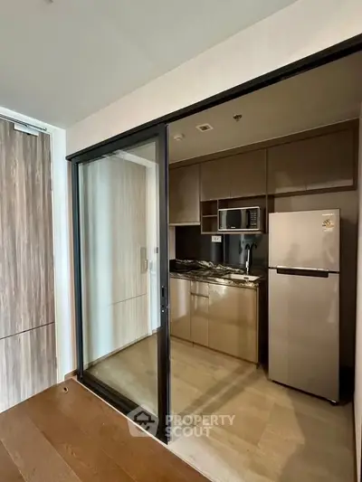 Modern kitchen with sleek appliances and wooden flooring in a stylish apartment.