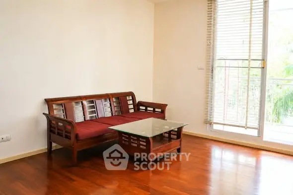 Spacious living room with wooden flooring and elegant furniture, featuring a cozy sofa and glass coffee table.
