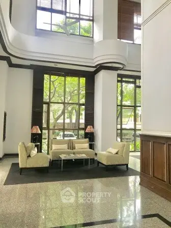 Elegant building lobby with modern seating and large windows overlooking greenery.