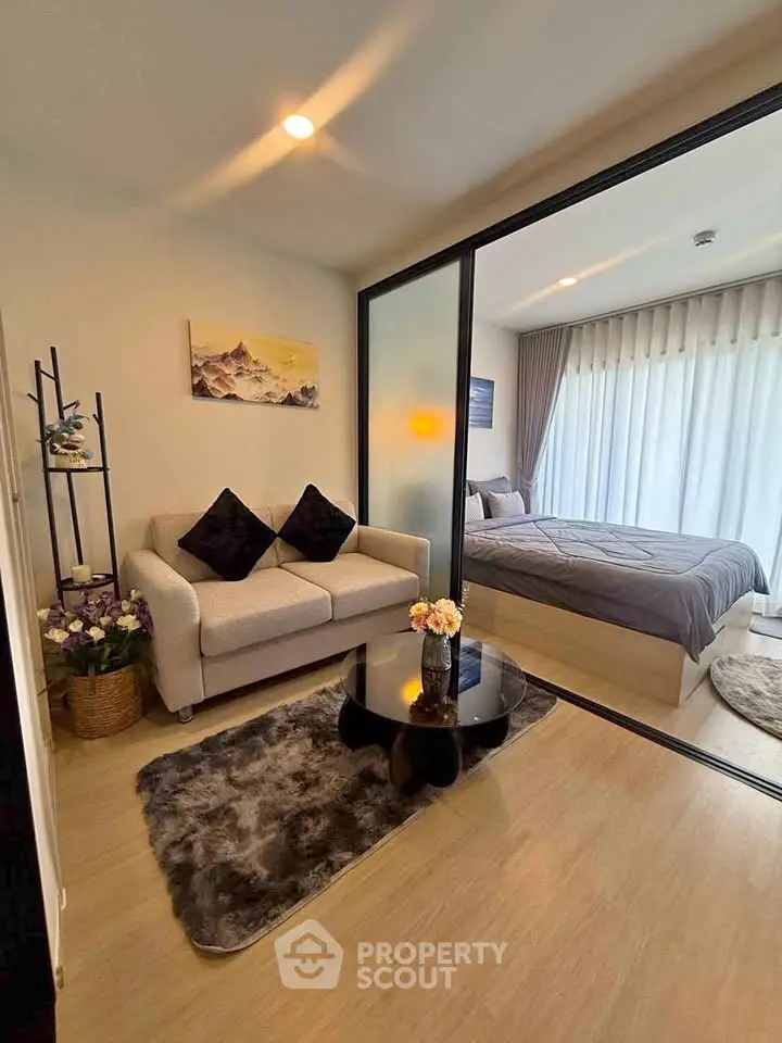 Modern studio apartment with cozy living area and bedroom separated by glass partition.