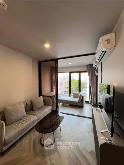 Modern living room with balcony view, featuring sleek furniture and air conditioning.