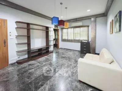Spacious living room with modern marble flooring and stylish shelving unit.