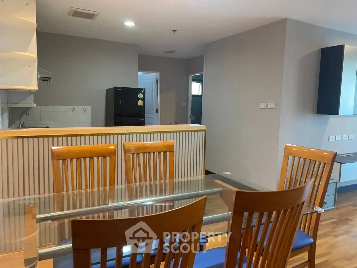 Spacious dining area with wooden furniture and modern kitchen in open layout apartment.