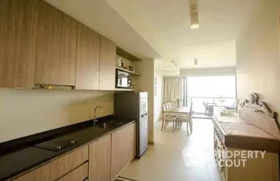 Modern kitchen with sleek cabinetry and open layout leading to dining area and balcony.