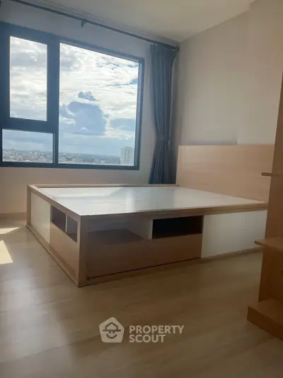 Spacious bedroom with large window offering stunning city views and modern wooden furniture.
