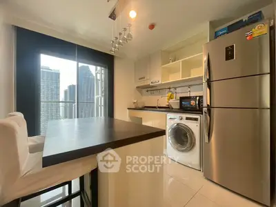 Modern kitchen with city view, featuring stainless steel appliances and a washing machine, ideal for urban living.