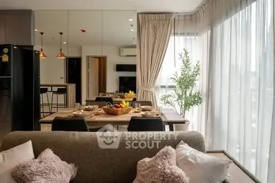 Modern living room with dining area and large windows, featuring cozy decor and natural light.