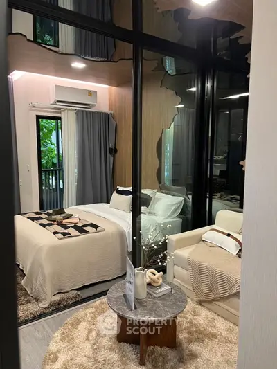 Modern bedroom with cozy decor and large windows overlooking greenery, featuring stylish furniture and neutral tones.