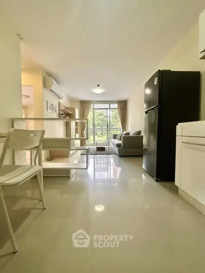 Spacious open-plan living room with modern kitchen and large windows for natural light.